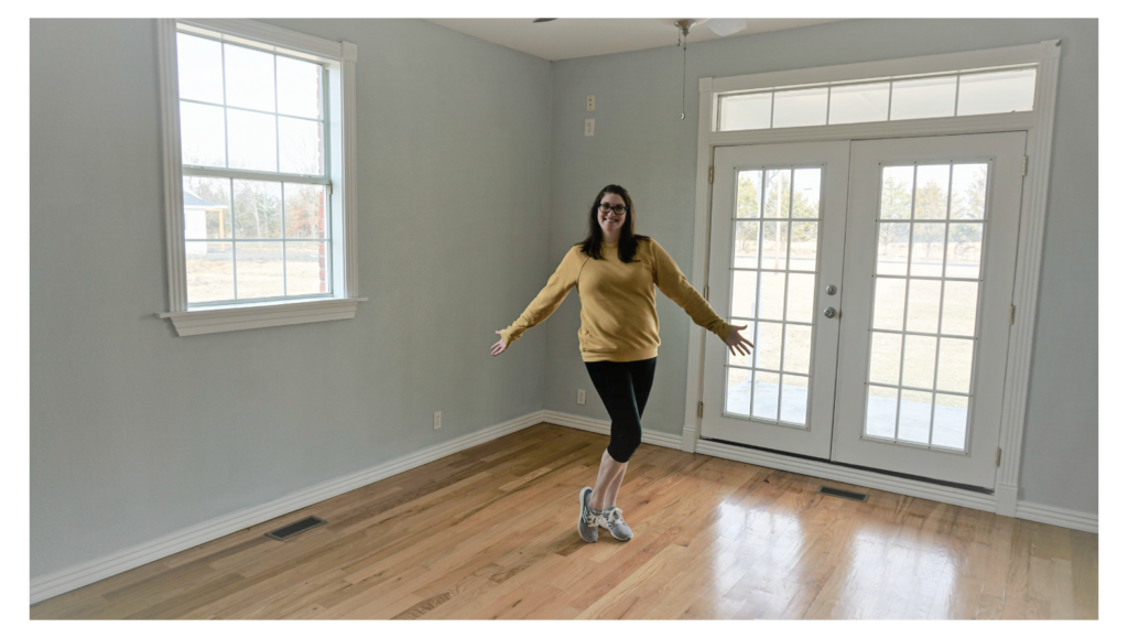 Woman standing in the center of an empty bedroom.