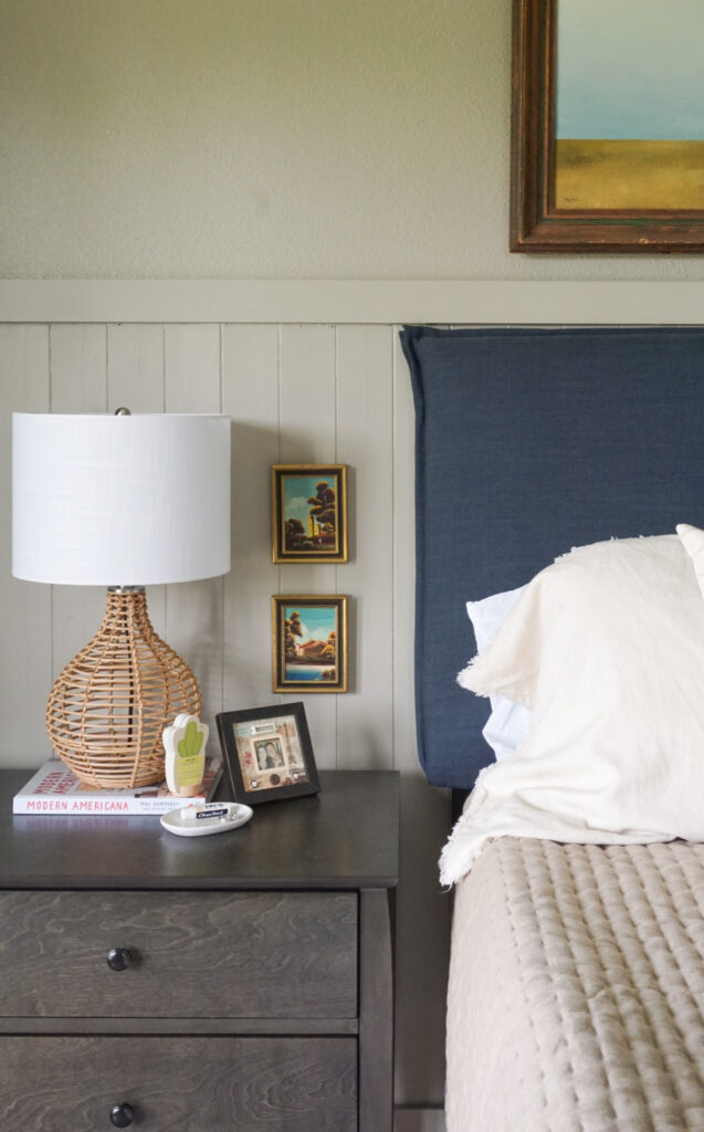 French seam blue headboard with a rattan lamp on a nightstand.