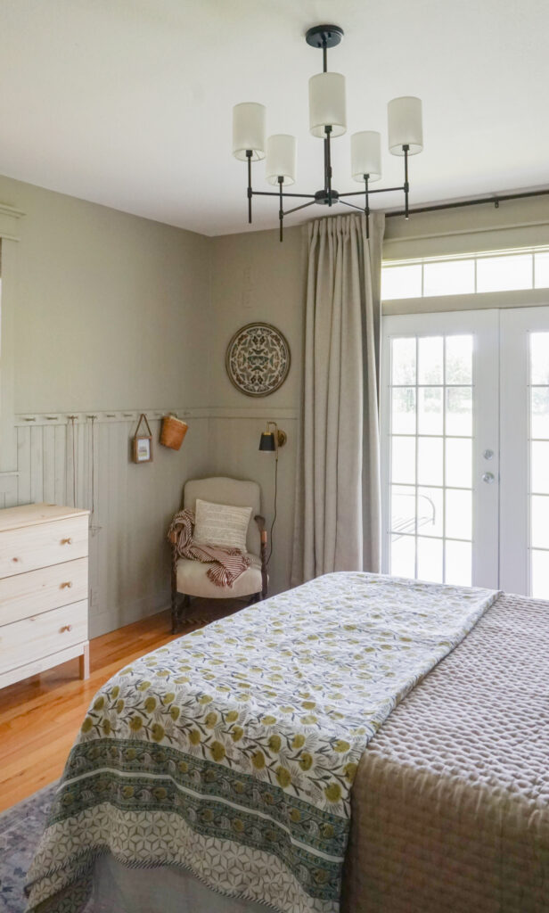 A bedroom with shiplap walls and a cozy chair in the corner. 