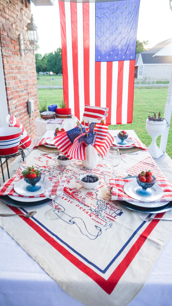 Red white and blue table setting with flags in the center and strawberries on the white plates