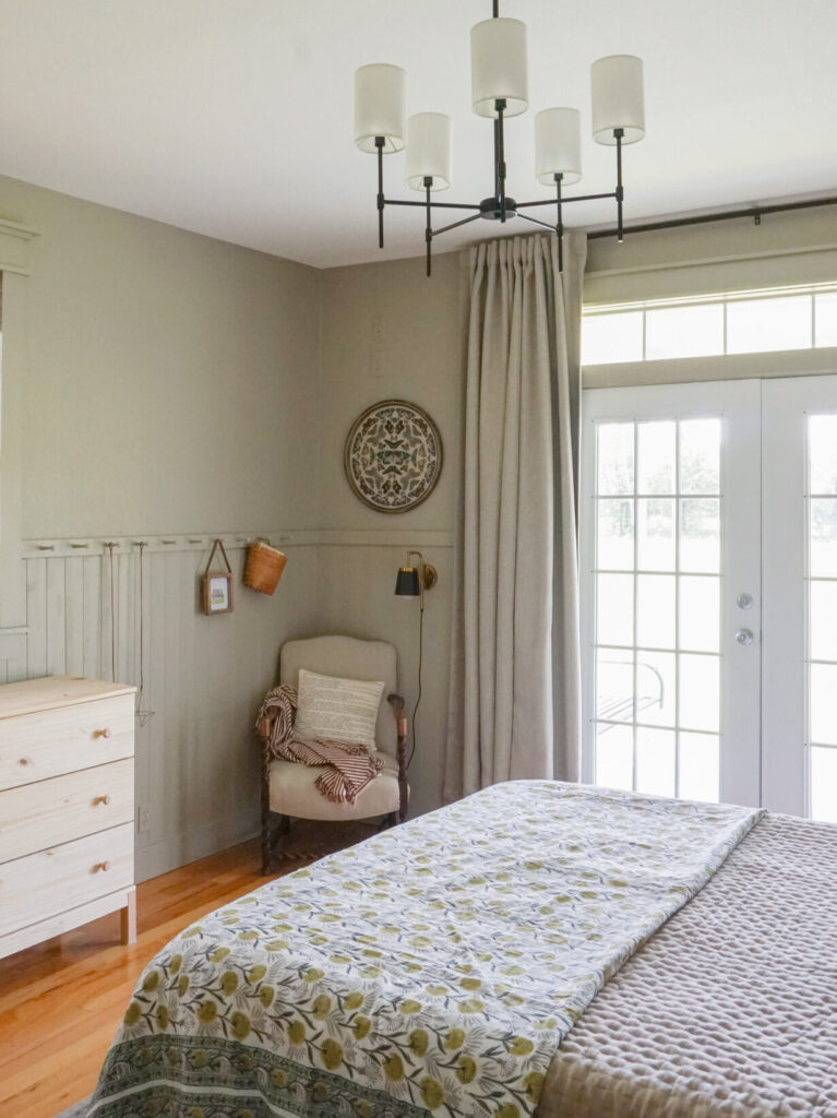 Light green bedroom with a block print quilt and thick linen drapes