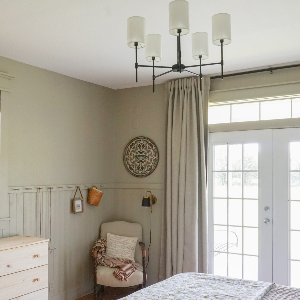 Light green bedroom with a block print quilt and thick linen drapes