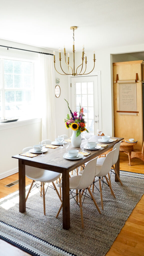 Handmade table with white chairs and a gold chandelier